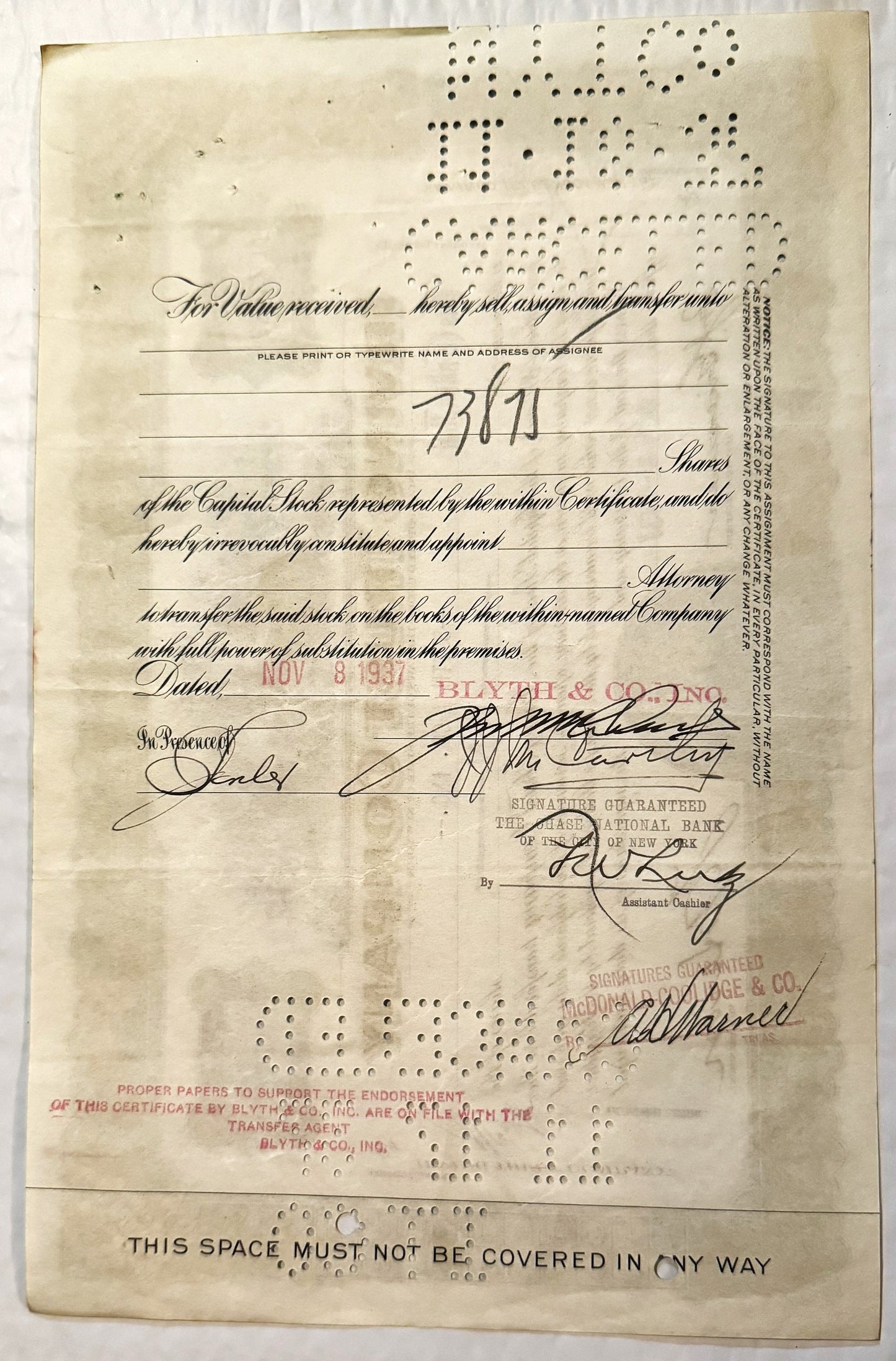 Aged stock certificate from with handwritten signatures, printed text, and perforated holes along edges, displayed flat