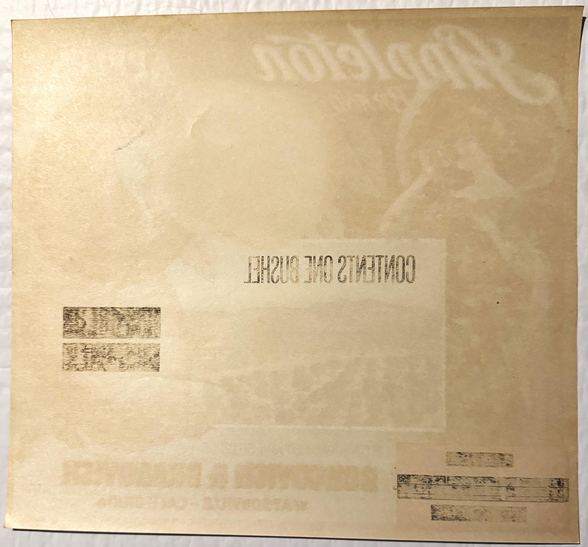 Aged cream-colored fruit crate label with reversed embossed text and faded stamps, photographed flat against white background