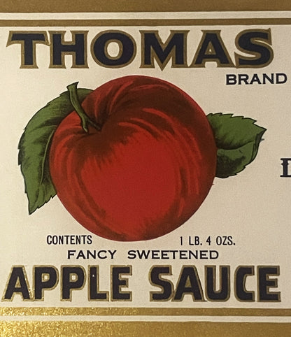 Antique Thomas Brand apple sauce can label featuring a large red apple with green leaves, gold and black text reading "Fancy Sweetened Apple Sauce," 1 lb. 4 oz., cream background with gold borders.
