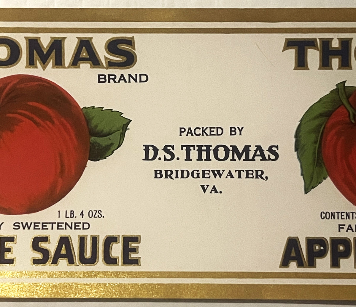 Antique Thomas brand apple sauce can label from Bridgewater, VA, showing red apples with green leaves, gold lettering, and text reading "Packed by D.S. Thomas," 1 lb. 4 oz. size.