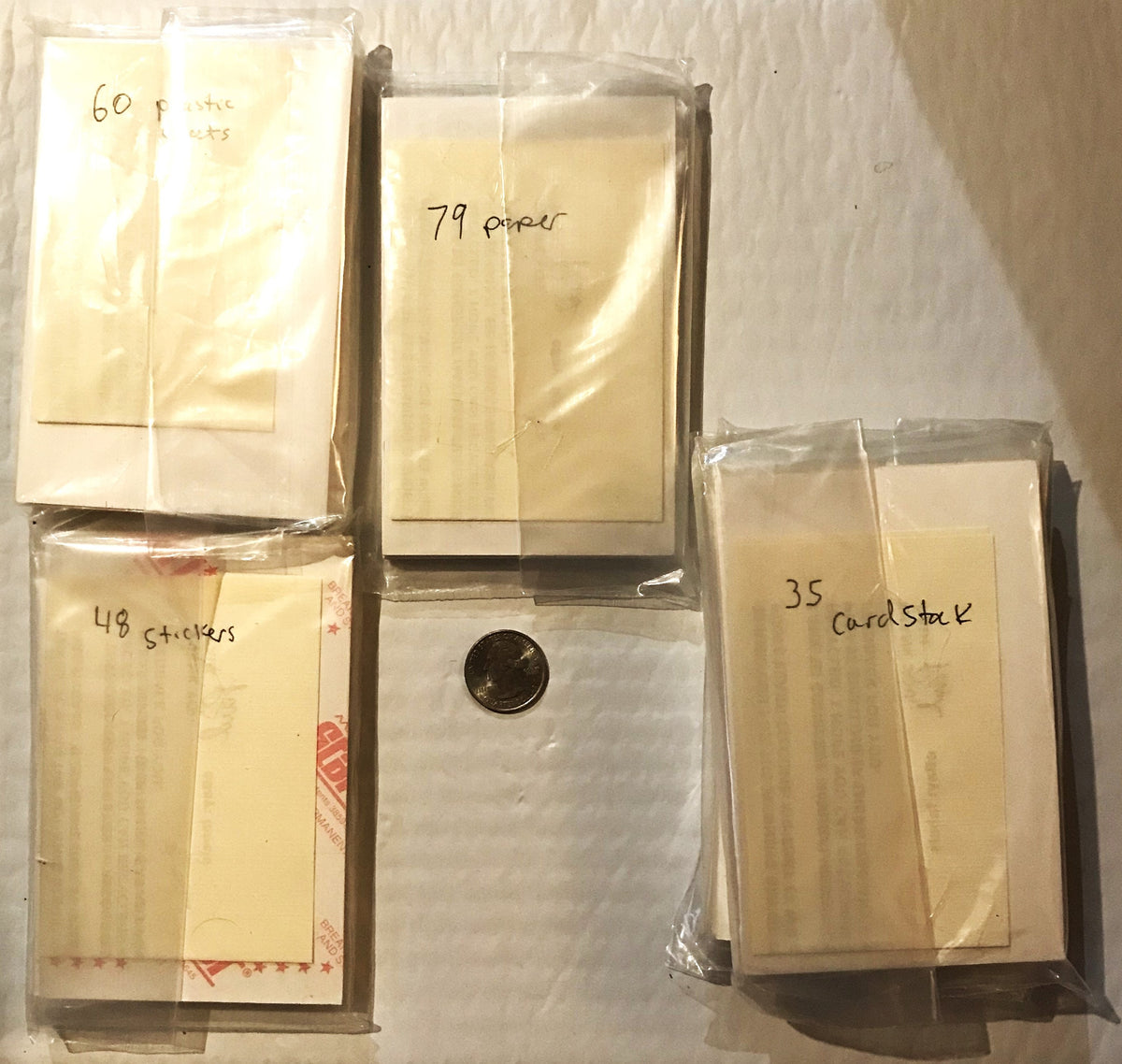 Four sealed plastic packages of vintage Coca-Cola promo cards labeled with handwritten quantities (60, 79, 48, 35), with a pe