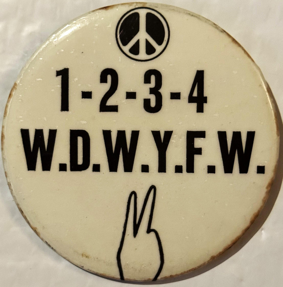 Cream-colored round pinback button with peace symbol at top, "1-2-3-4 W.D.W.Y.F.W." text, peace hand gesture at bottom, shown