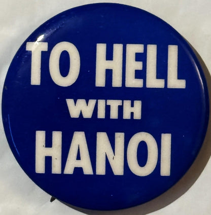 Deep blue circular pinback button with white capital letters reading "TO HELL WITH HANOI" against neutral background