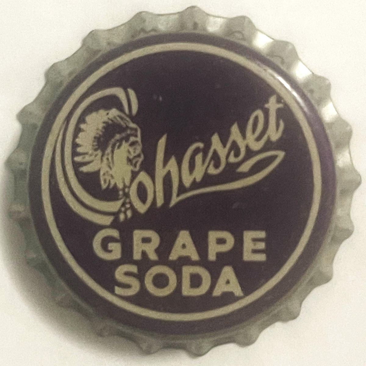 Cohasset Grape Soda crown bottle cap: a Native American head in a feathered headdress inside the script C of Cohasset, GRAPE SODA below, cream on deep purple