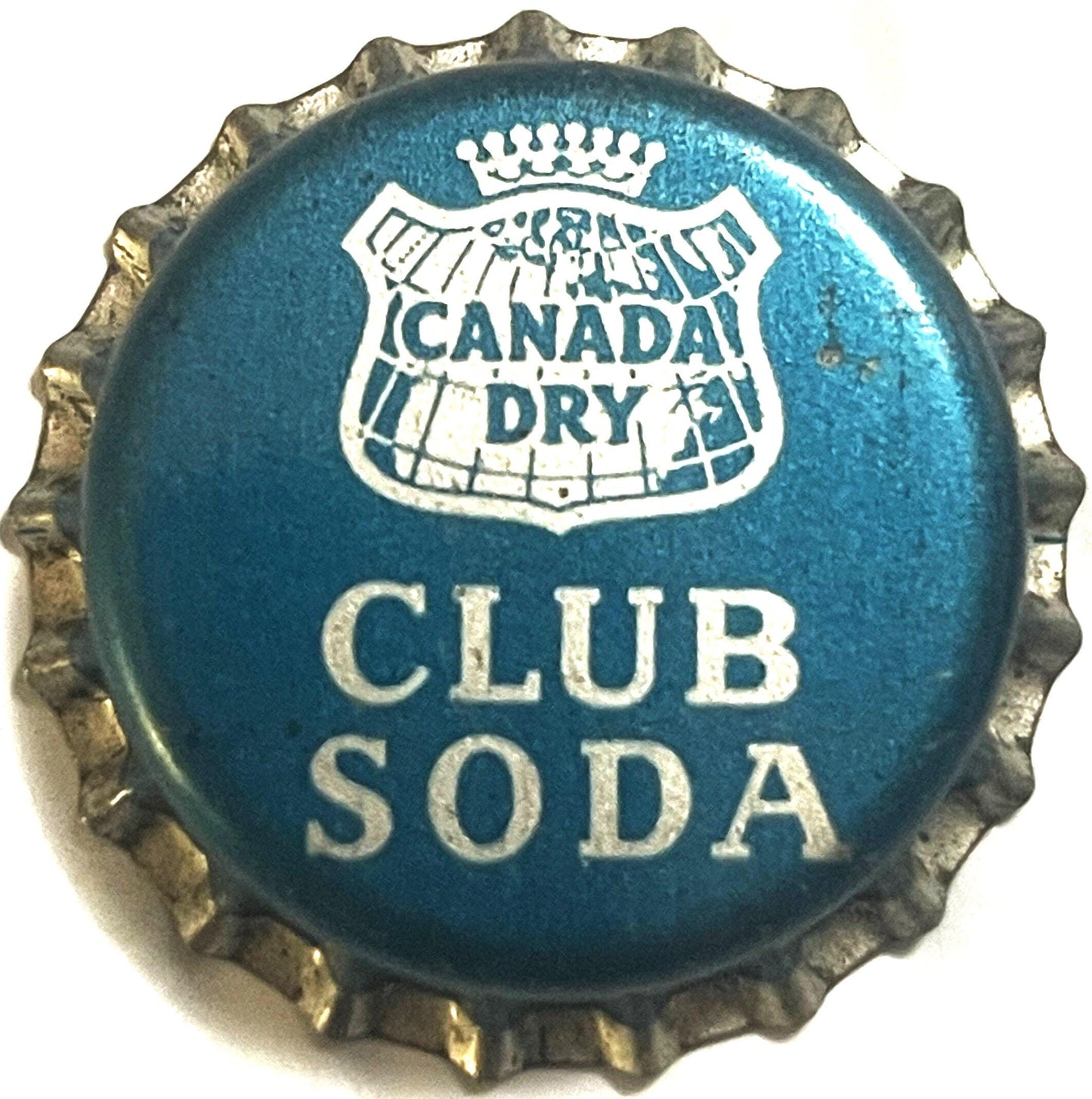 Vintage Canada Dry Club Soda bottle cap with blue background, white crown logo, and corrugated metal rim, shown flat against 