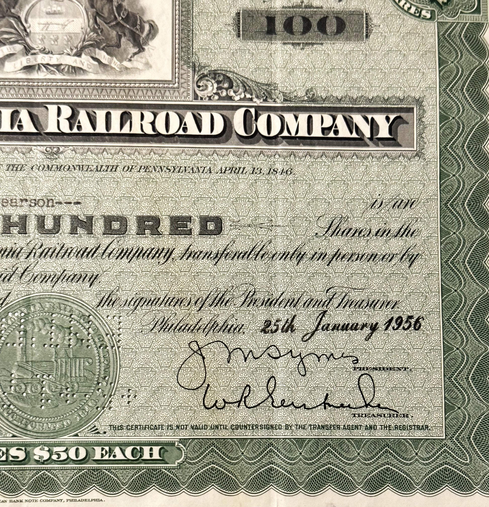 Close-up of vintage Pennsylvania Railroad Company stock certificate showing "100" denomination, ornate border design, officia