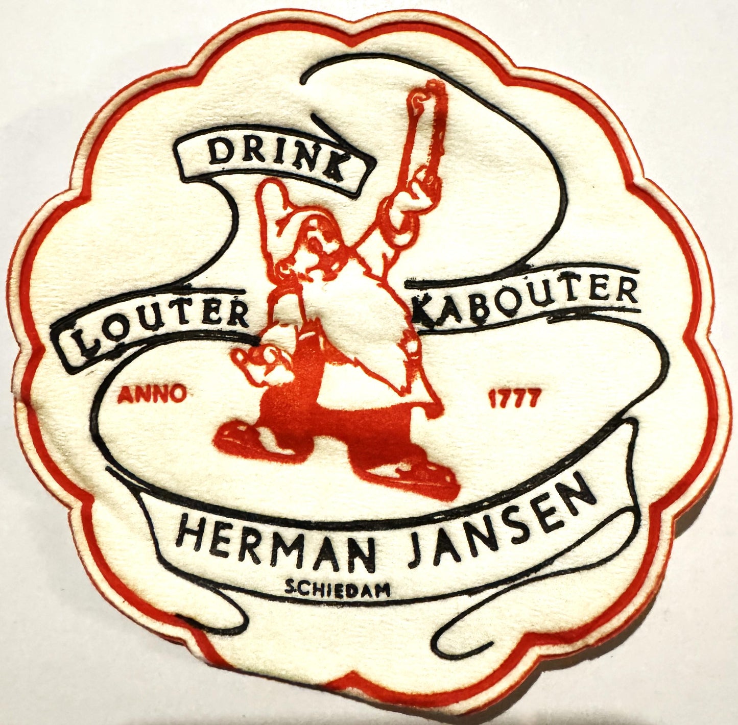 Vintage cloth coaster with red and cream scalloped edge, featuring red leprechaun illustration and text "Drink Louter Kaboute