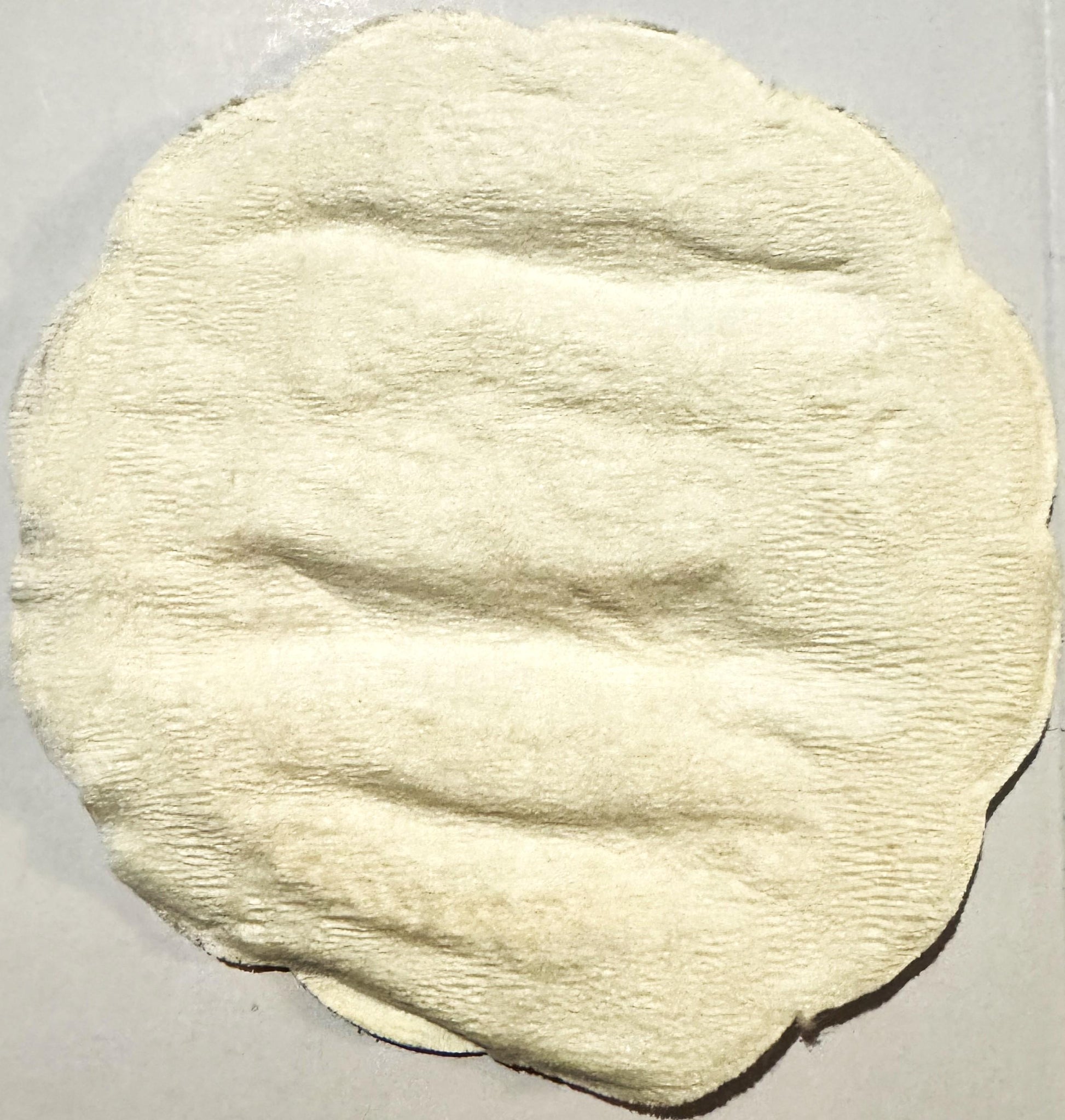 Cream-colored embossed cloth coaster with horizontal ribbed texture and rounded edges, showing a woman's profile drinking fro