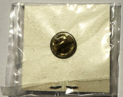 Factory-sealed clear plastic package containing a round brass campaign pin with "AuH2O" text visible on cream-colored backing