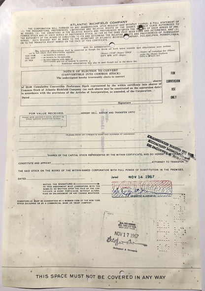 Cream-colored Atlantic Richfield convertible stock certificate with printed text, signature, and dated stamps in blue an