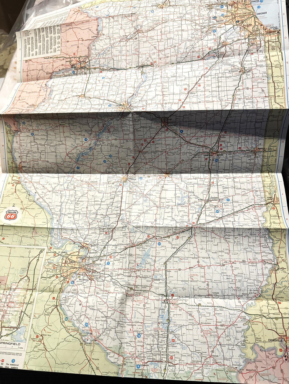 Flat lay of four folded vintage Route 66 maps showing Illinois sections with red and blue highways, town names, and grid patt