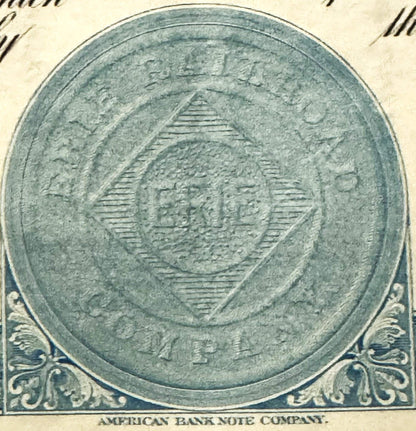 Circular vignette featuring ornate shield design with horizontal lines, surrounded by decorative blue scrollwork corners and 
