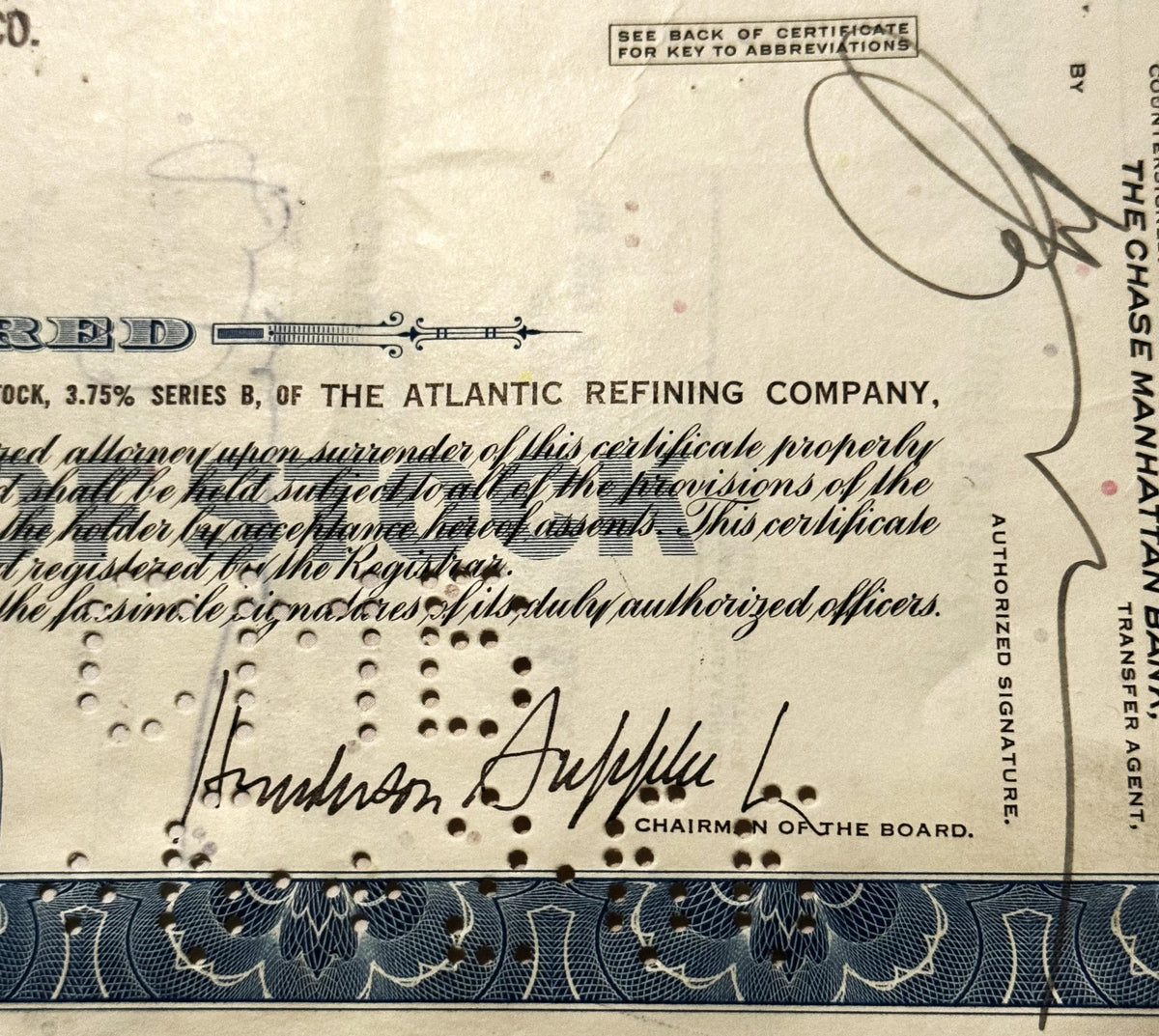 Vintage stock certificate from Atlantic Refining Company with printed text, decorative blue border, handwritten signature, an