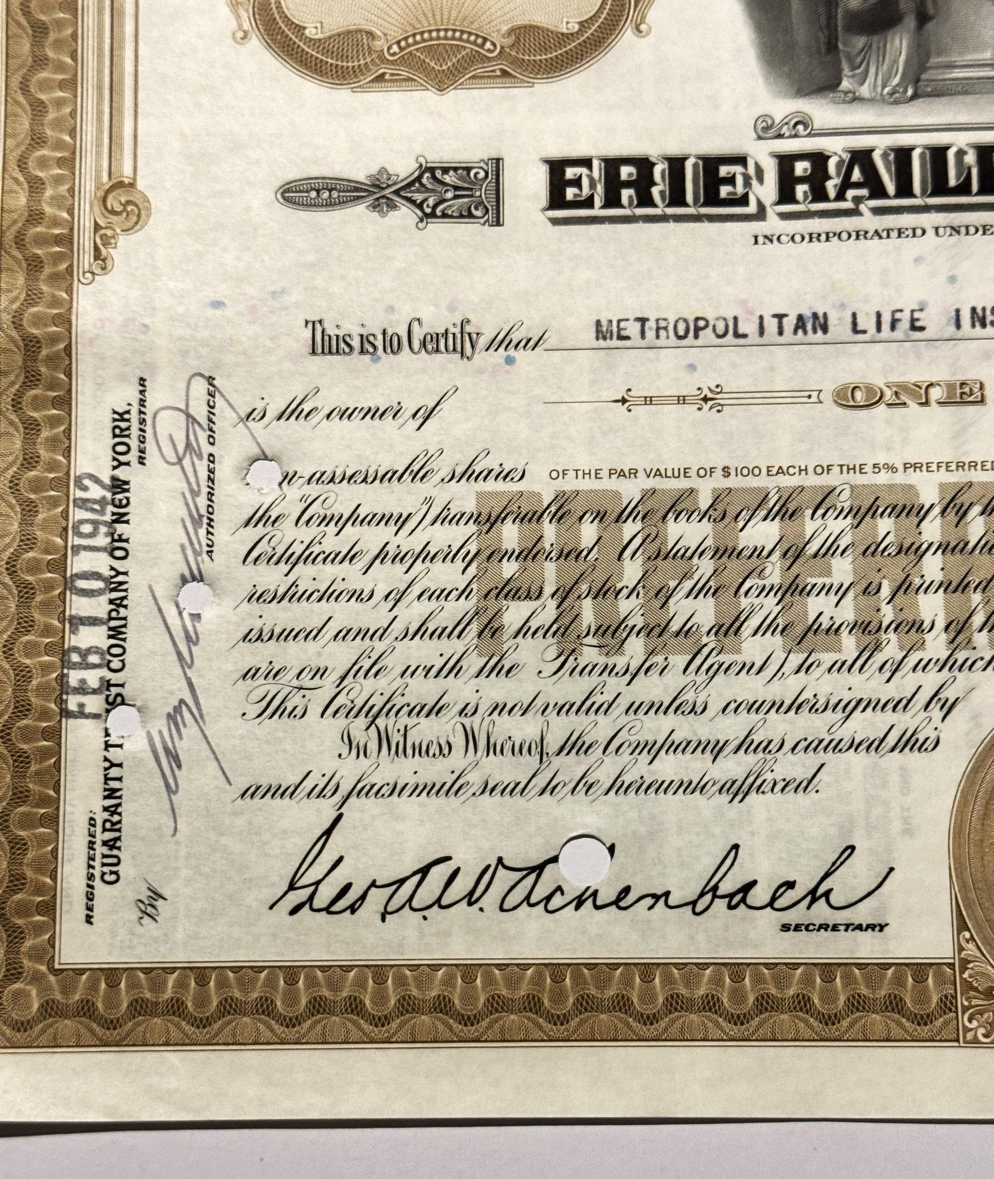Close-up of vintage Erie Railroad stock certificate showing ornate border, "Metropolitan Life Insurance" text, secretary sign