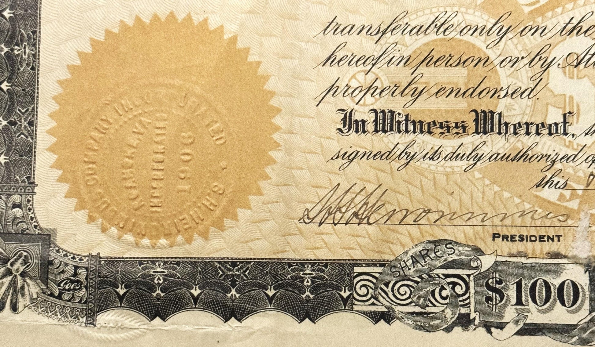 Close-up of vintage stock certificate showing gold embossed seal, cursive text, "In Witness Whereof" heading, president signa