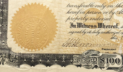 Close-up of vintage stock certificate showing gold embossed seal, cursive text, "In Witness Whereof" heading, president signa