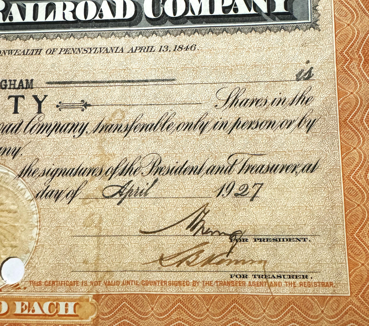 Close-up of Pennsylvania Railroad stock certificate showing signatures, ornate beige background with repeating pattern