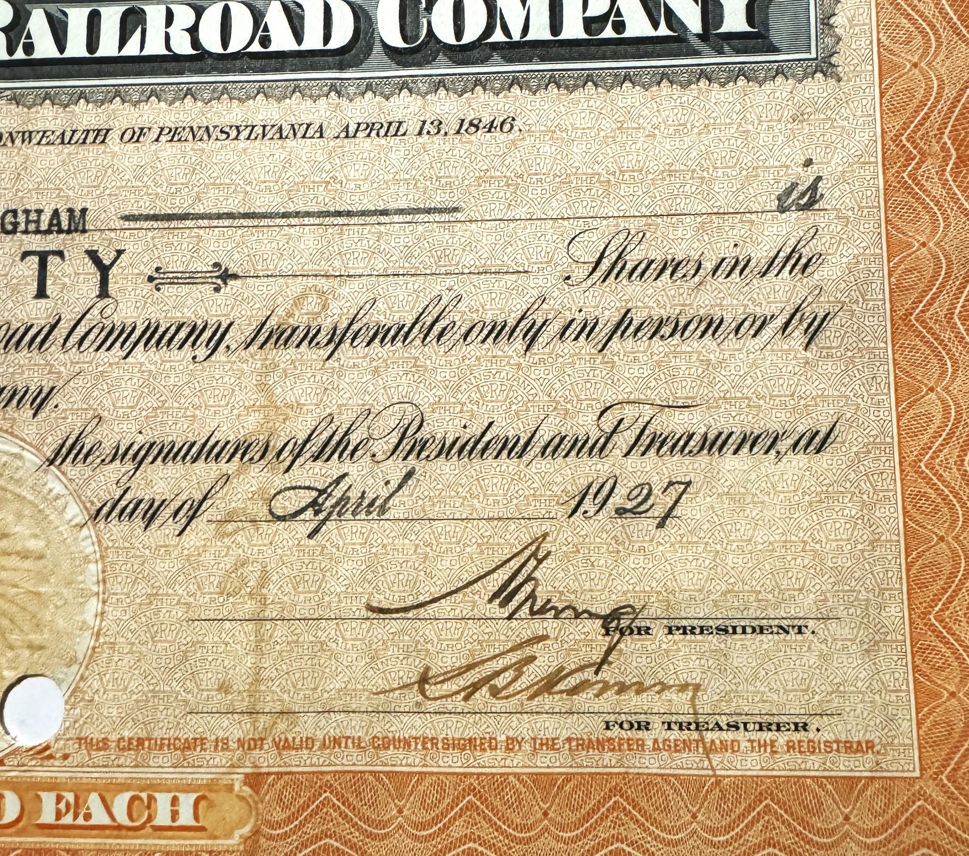 Close-up of Pennsylvania Railroad stock certificate showing signatures, ornate beige background with repeating pattern