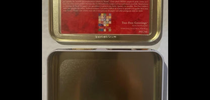 The tin open and empty: no note cards included, just the bare metal card well below the red Tree-Free kenaf-paper story card mounted inside the lid.