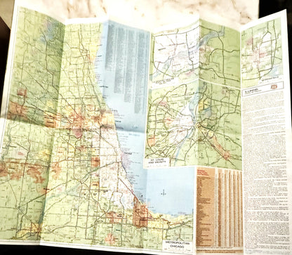 Opened vintage Route 66 Illinois map with green and tan coloring, Chicago area detail, and informational text pages visible o