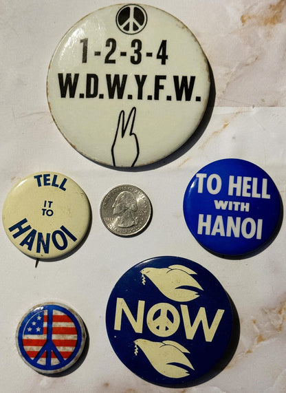 Six vintage anti-war pinback buttons arranged on white surface with quarter for scale, featuring peace symbols, doves, and sl
