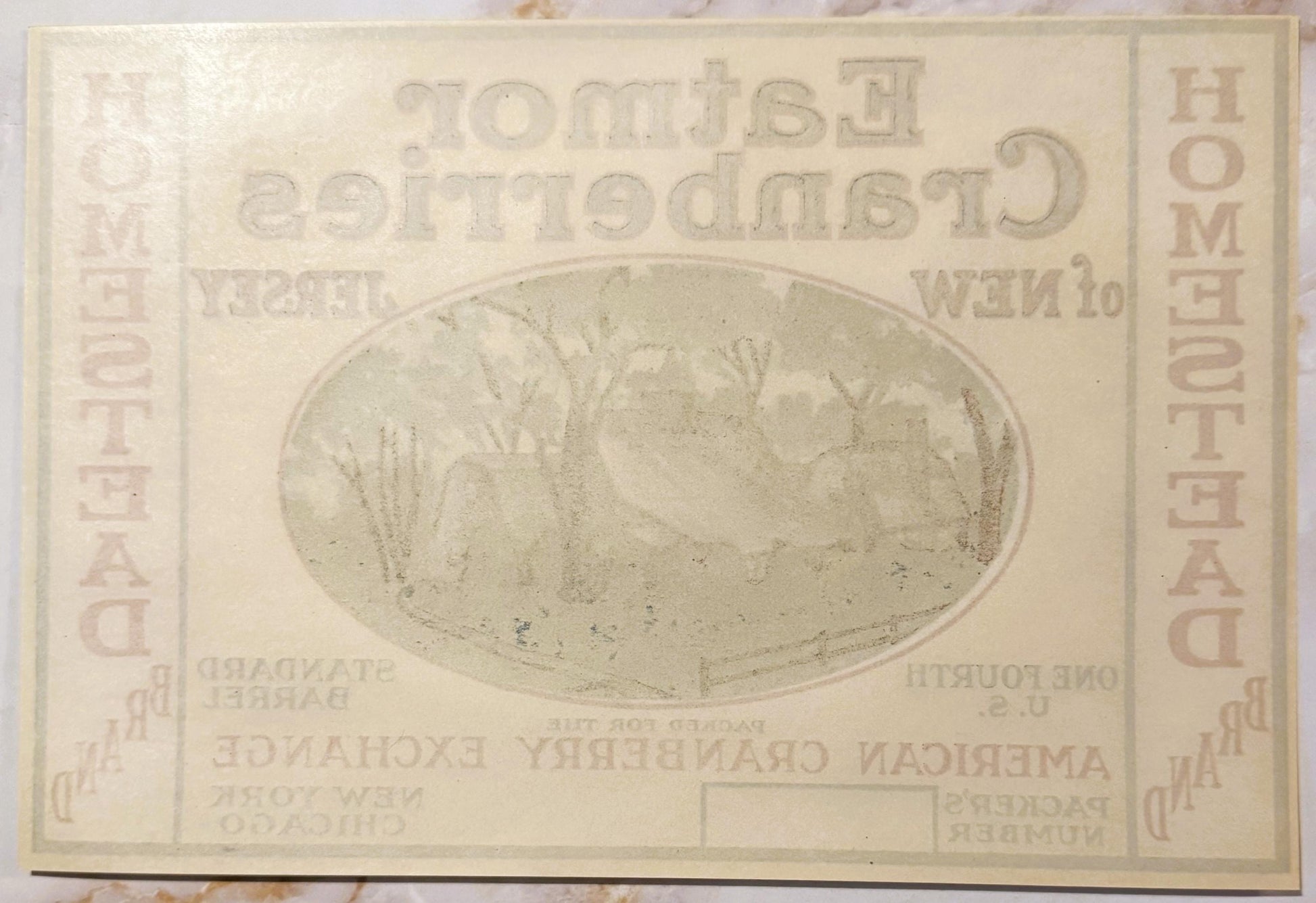 Cream-colored vintage cranberry barrel label with oval landscape illustration and embossed text, showing age spots and wear