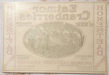 Cream-colored vintage cranberry barrel label with oval landscape illustration and embossed text, showing age spots and wear
