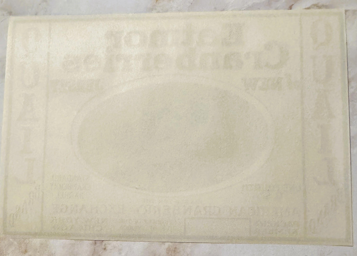 Cream-colored vintage cranberry label with embossed text and decorative border, photographed flat against light background