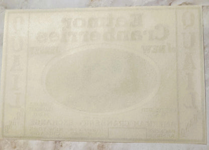 Cream-colored vintage cranberry label with embossed text and decorative border, photographed flat against light background