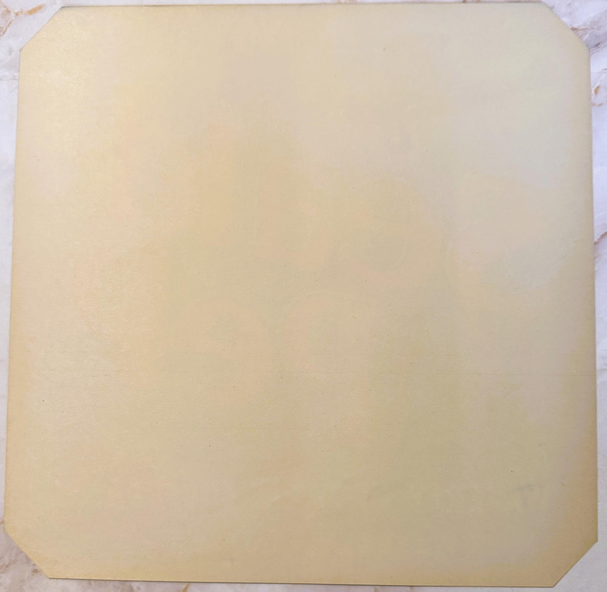 Blank cream-colored vintage crate label with rounded corners on marble surface