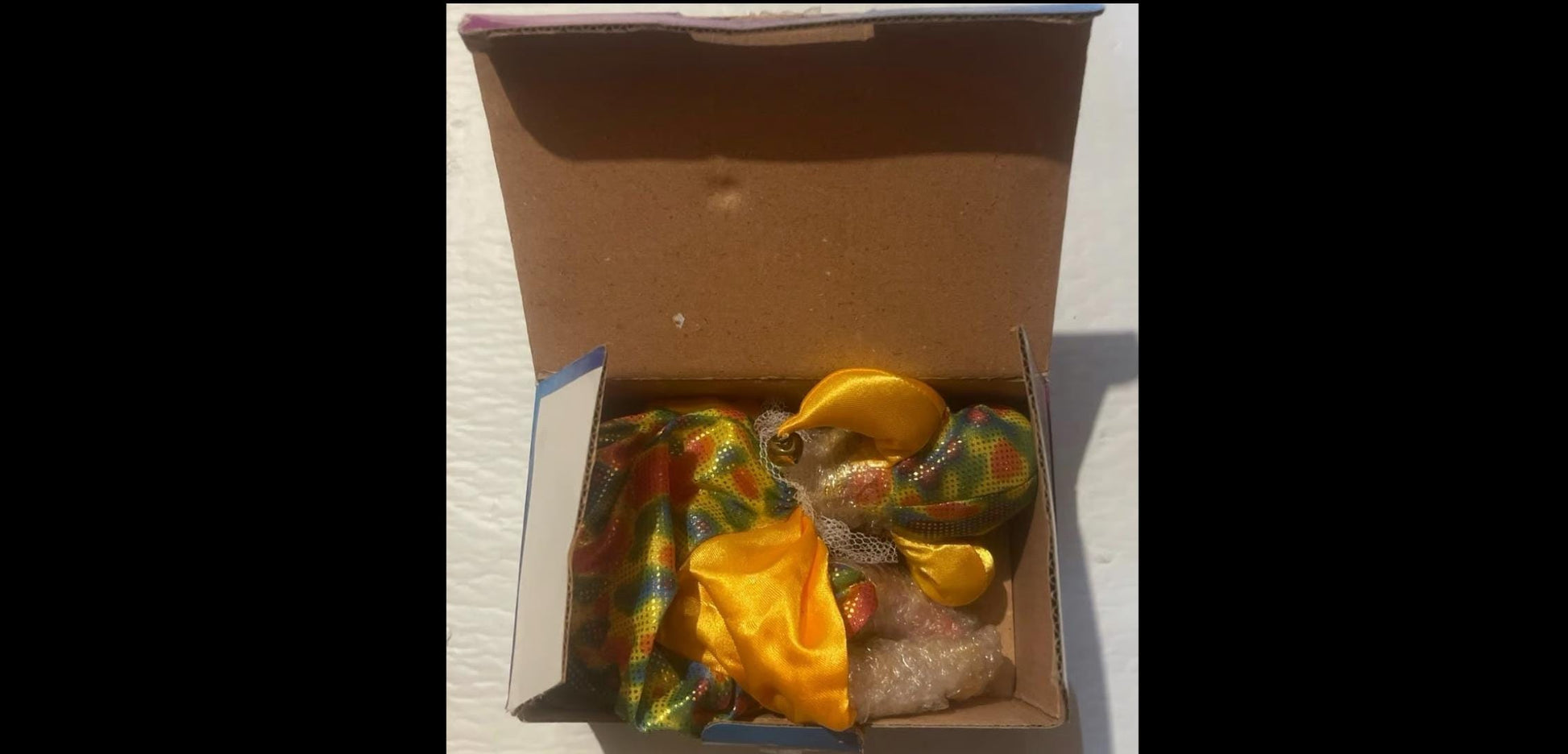 Open cardboard takeout box with wrapped food and citrus garnish beside Rare 1981 Porcelain Clown Doll
