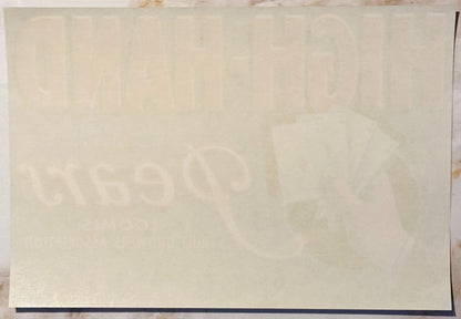 Cream-colored vintage crate label with faint watermarked design featuring playing cards and text, shown flat against neutral 