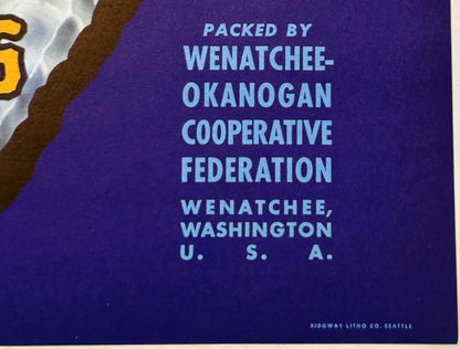 Close-up of blue crate label text reading "Packed by Wenatchee-Okanogan Cooperative Federation, Wenatchee, Washington U.S.A.