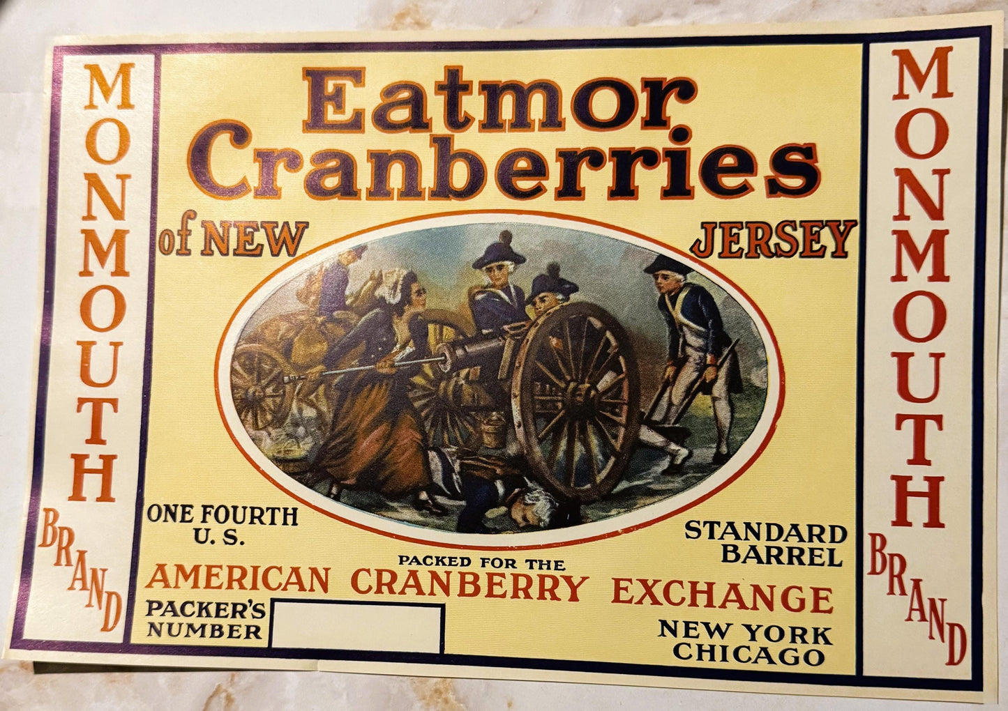 Vintage Monmouth Brand cranberry barrel label featuring colonial figures with cart, orange and red text on cream background