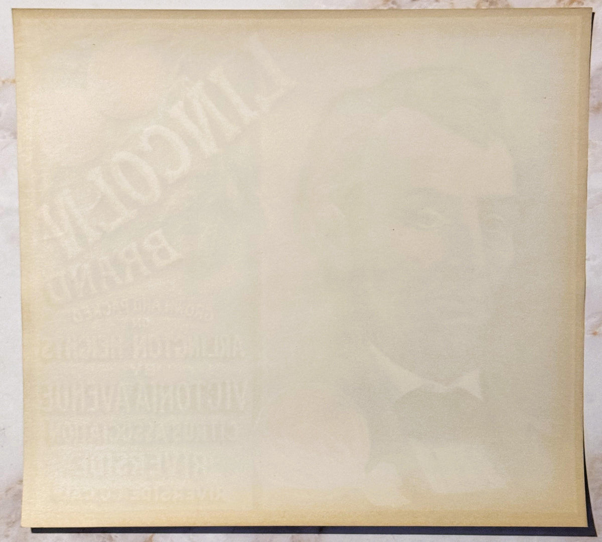 Cream-colored vintage crate label with faint embossed imagery and text, photographed flat against white background with dark 