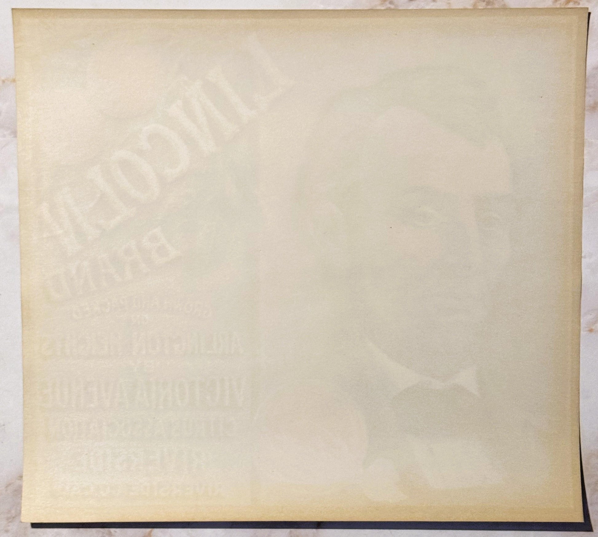 Cream-colored vintage crate label with faint embossed imagery and text, photographed flat against white background with dark 