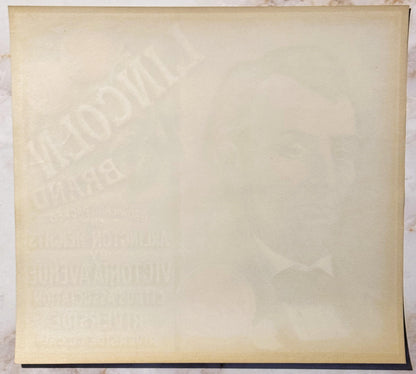 Cream-colored vintage crate label with faint embossed imagery and text, photographed flat against white background with dark 