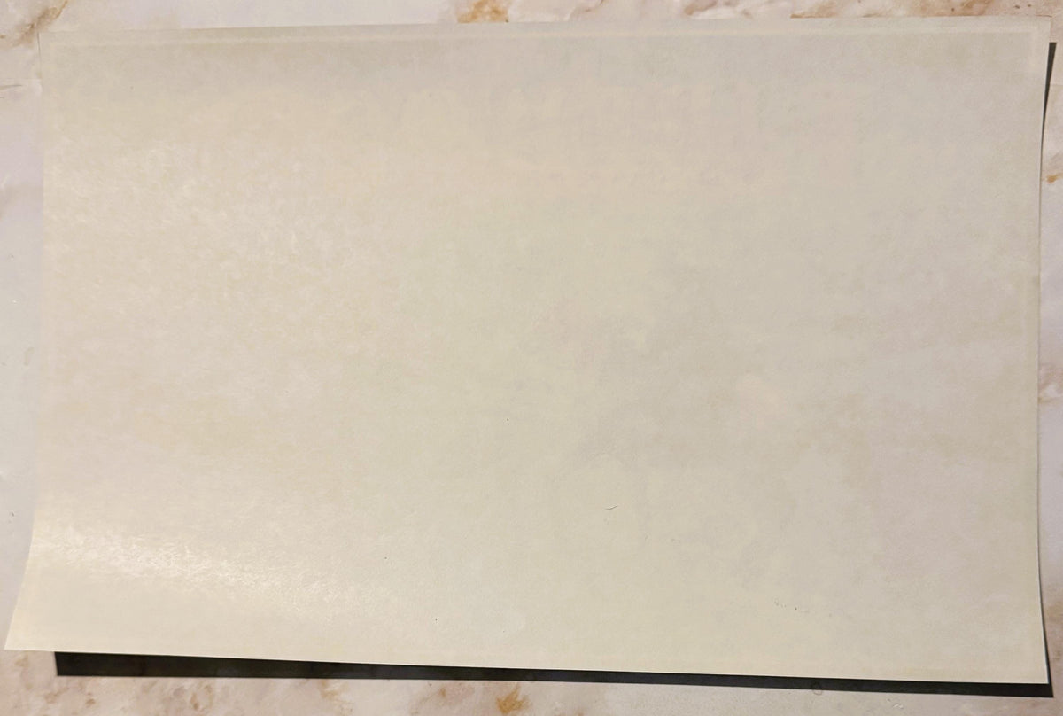 Cream-colored vintage crate label with black border stripe along bottom edge, displayed flat on textured surface