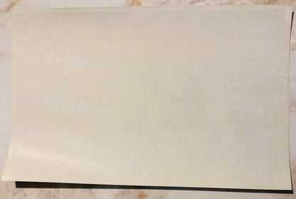 Cream-colored vintage crate label with black border stripe along bottom edge, displayed flat on textured surface