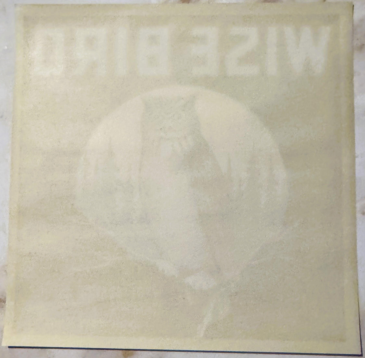 Cream-colored vintage citrus crate label with faded owl illustration and text, shown flat against white background