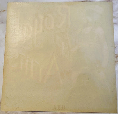 Cream-colored vintage crate label with embossed Royal Arms design and faint text, photographed flat on marble surface