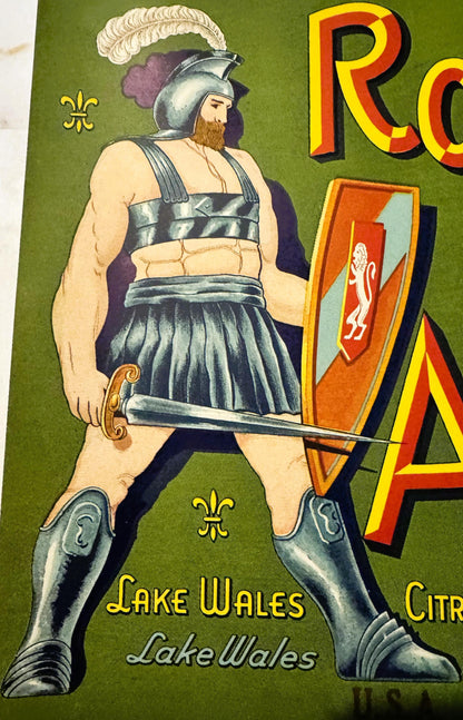 Vintage fruit crate label featuring a bearded warrior in Roman armor and pleated skirt holding a sword, on green background w
