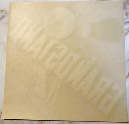Cream-colored vintage citrus crate label with faint embossed design, photographed flat on marble surface