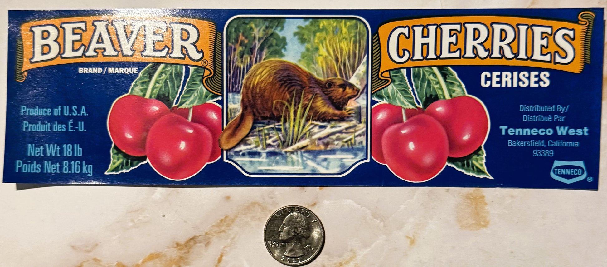 Vintage Beaver Brand Cherries crate label with beaver illustration, red cherries, and bilingual text, shown with quarter for 