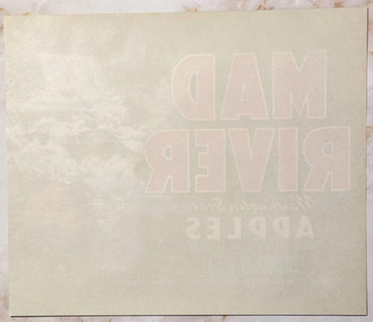 Cream-colored vintage apple crate label with embossed text reading "MAD RIVER" and additional text below, photographed flat a