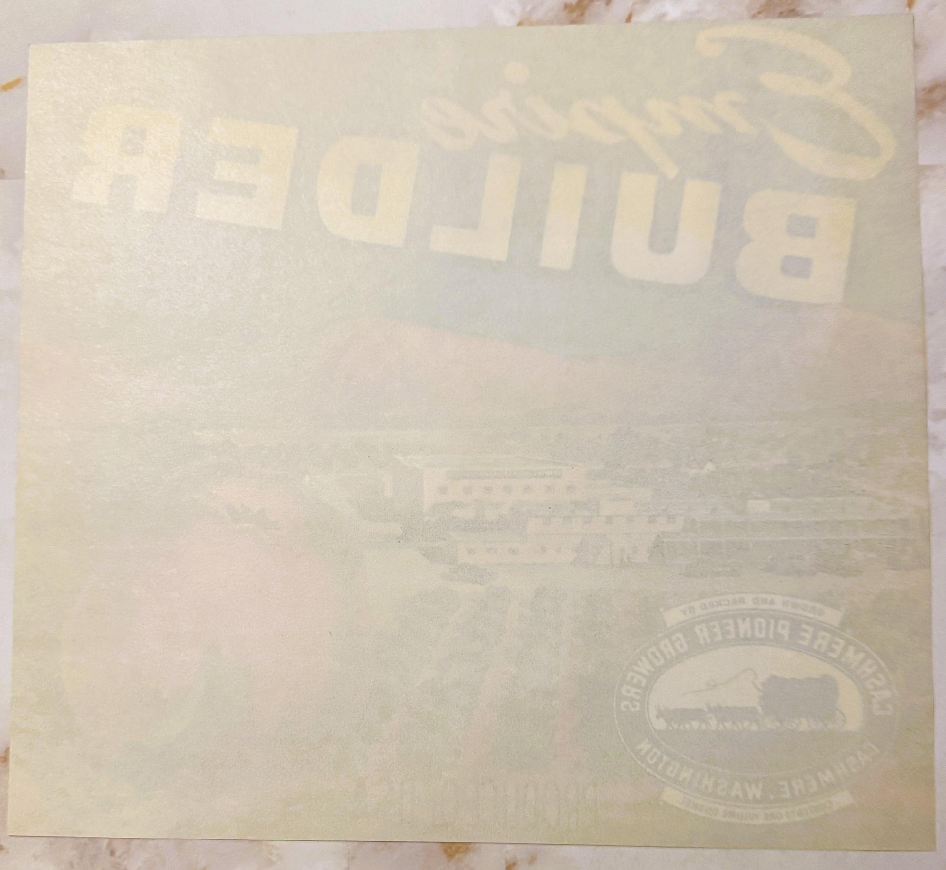 Cream-colored vintage apple crate label with "Empire Builder" text and railroad logo, photographed flat on marble surface
