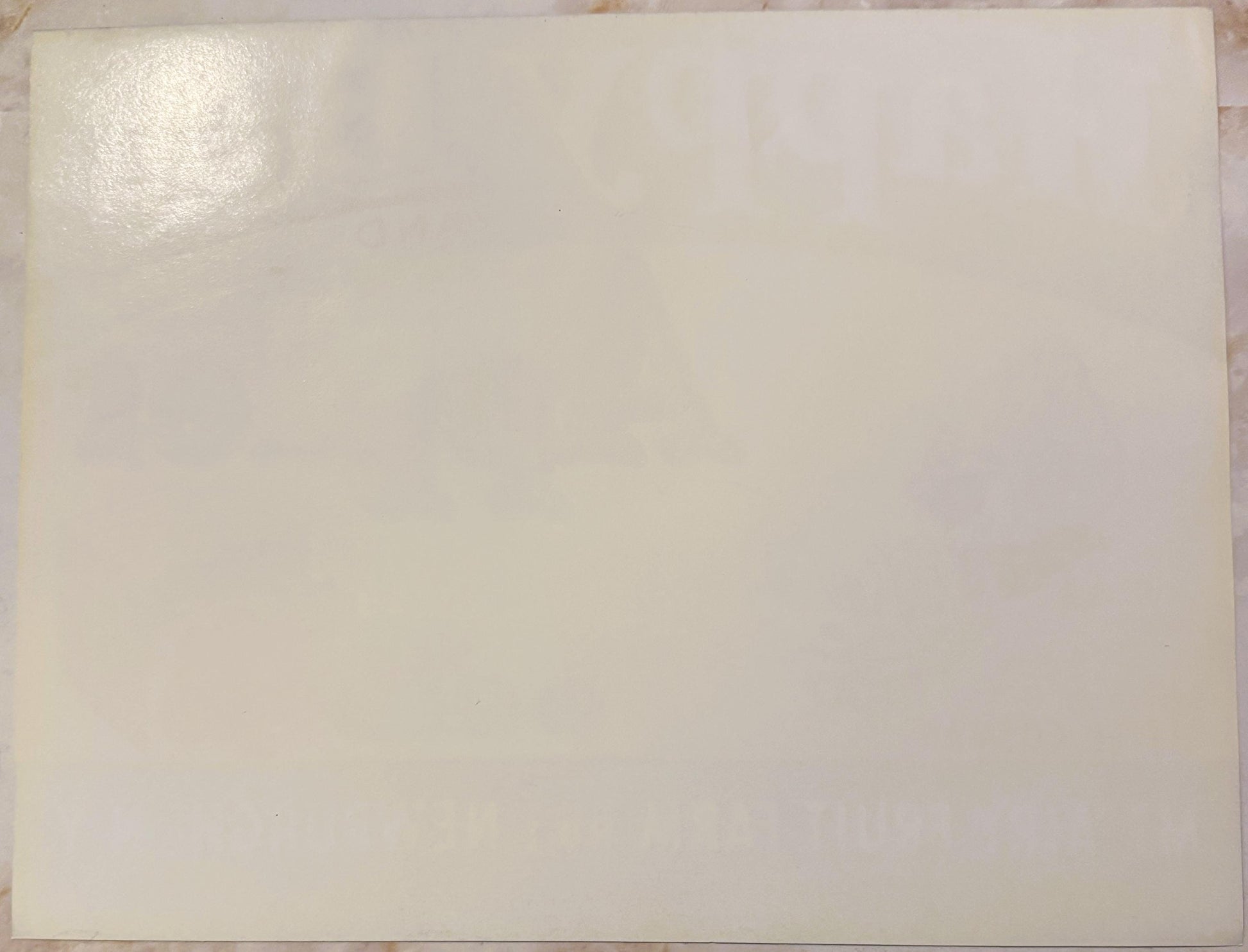 Blank cream-colored vintage apple crate label with slight shine in upper left corner, laid flat on wooden surface