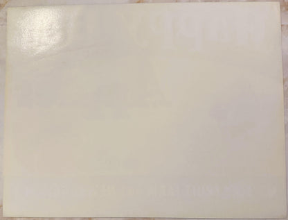 Blank cream-colored vintage apple crate label with slight shine in upper left corner, laid flat on wooden surface