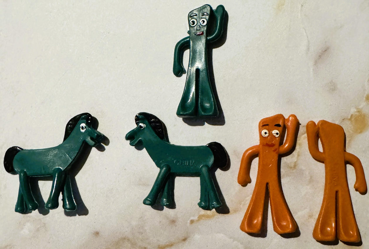 Set 1, the full group of five molded plastic figures on a white surface: one teal Gumby with a raised arm, two teal Pokey horses, and two orange-brown Gumby figures, each about two inches tall