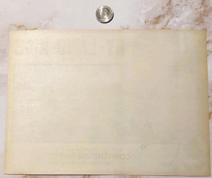 Cream-colored vintage fruit label next to quarter for scale, showing faded printing and aged paper with stains